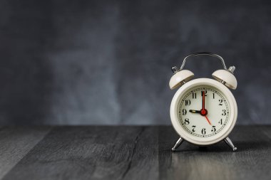Saat 5 ' te saati 9 ' da alarmda. Koyu arka planda kopya alanı ile ahşap masada Vintage/Retro beyaz analog çalar saat