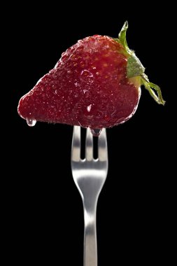 Siyah arka plan üzerinde izole gümüş çatal üzerinde su damlaları ve şeker ile taze çilek. Yemek fotoğrafçılığı
