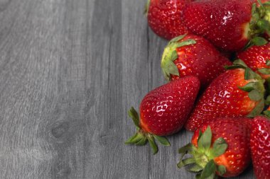 Kopya alanı ile ahşap gri masa üzerinde taze çilek yığını. Gıda fotoğrafçılığı arka plan