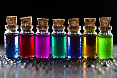 Siyah arka plan üzerinde izole şeffaf renkli kimyasal sıvı ile küçük şişe satır