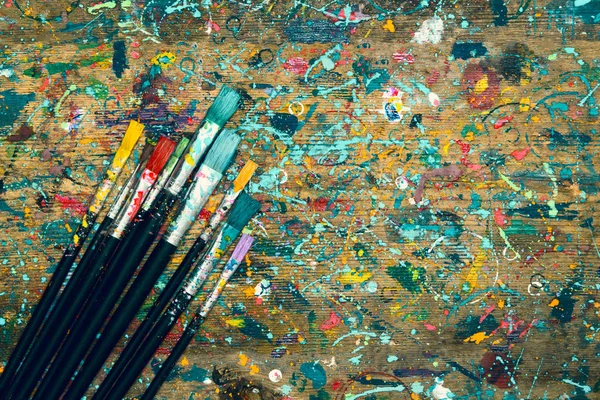トップビュー 古い染色されたアーティストテーブルとコピースペースを持つペイントブラシ 芸術的背景 — ストック写真
