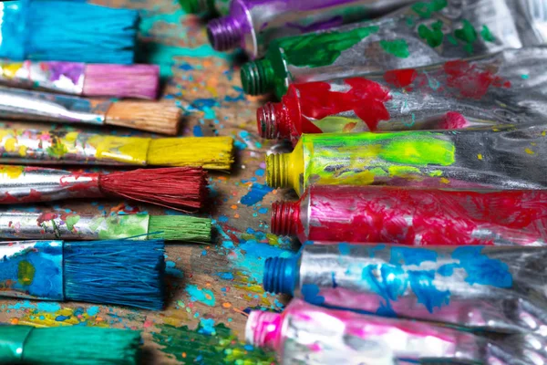 Sanatçı masasında lekeli boya fırçaları ve akrilik ağrı tüpleri. Sanatsal arka plan