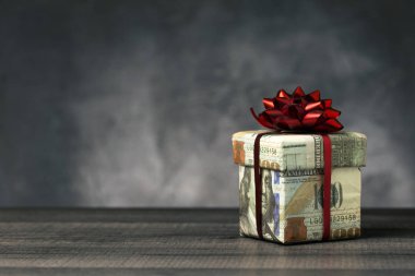 Hediye kutusu 100 Amerikan doları banknot ve kopya alanı ile ahşap masa üzerinde kırmızı kurdele sarılmış