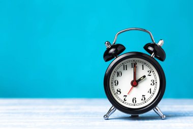 Kopya alanı ile mavi arka plan üzerinde Retro siyah çalar saat. Saat 7'de saat 2'de alarm