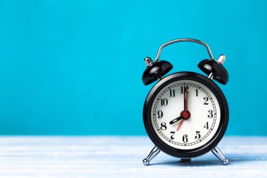 Kopya alanı ile mavi arka plan üzerinde Retro siyah çalar saat. Saat 7'de saat 8'de alarm