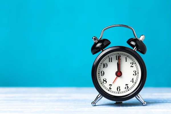 Kopya alanı ile mavi arka plan üzerinde Retro siyah çalar saat. Saat 7'de saat 12'de alarm
