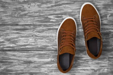 Ahşap zemin üzerinde kopya alanı olan kahverengi deri ayakkabılar.