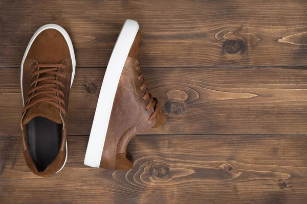 Ahşap zemin üzerinde kopya alanı olan kahverengi deri ayakkabılar.