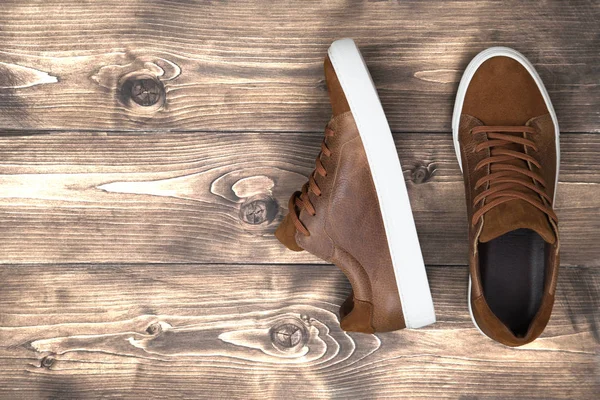 Ahşap zemin üzerinde kopya alanı olan kahverengi deri ayakkabılar.