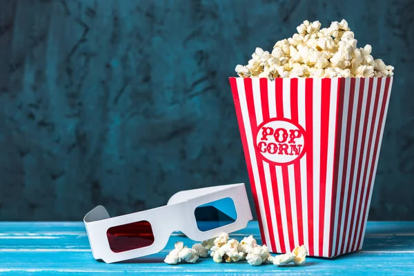 Popcorn bucket and 3D glasses with copy space on blue background