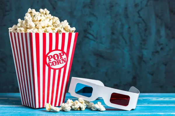 Popcorn bucket and 3D glasses with copy space on blue background