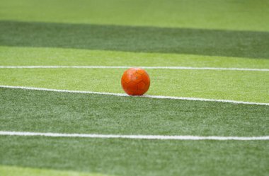 Yapay yeşil çim alanında turuncu futbol topu