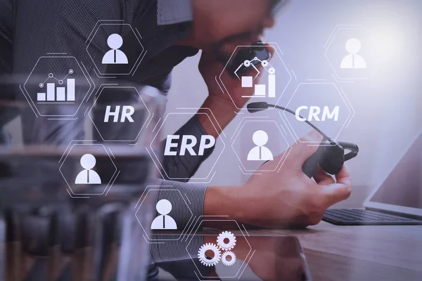 Architecture of ERP (Enterprise Resource Planning) system with connections between business intelligence (BI), production, CRM modules and HR diagram.Man using VOIP headset with digital tablet computer.