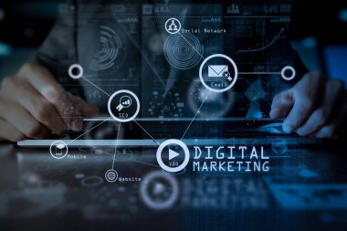 Dijital medya pazarlama (Web sitesi reklam, e-posta, sosyal ağ, Seo, video, mobil app) dijital katman iş stratejisi ve sosyal medya diyagramı ahşap masa üzerinde olan dizüstü bilgisayar üzerinde çalışan sanal screen.business adam elinde.  