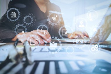 E-öğrenme bağlı Dişli çarkları ile diyagram sanal dashboard.business belgeler ofis masası üzerinde olan dizüstü bilgisayar ile akıllı telefon ve grafik iş diyagram ve arka planda çalışan adam bağlı