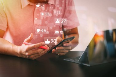 Sosyal medya ve pazarlama sanal simgeleri ekran concept.businessman pembe tişört akıllı telefon ve digitl tablet bilgisayar cam ile modern ofis ahşap masa üzerinde çalışma içinde görünüm yansıyan