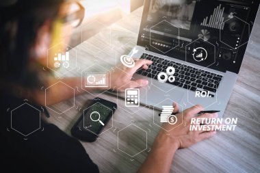 Yatırım getirisi getirisi yatırım göstergesi iş geliştirmek için sanal tablosu içinde. tasarımcı el dizüstü bilgisayar ve ofis masasında akıllı telefon ile video konferans katılıyor