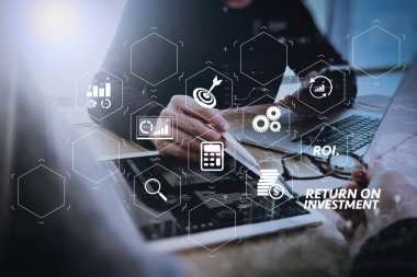 Yatırım getirisi getirisi yatırım göstergesi iş geliştirmek için sanal tablosu içinde. veri ve akıllı telefon ve tasarım diyagramı ile dijital tablet ve bilgisayar laptop mermer masasında tartışan iki meslektaşım web tasarımcısı.