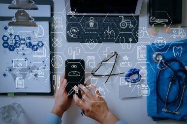 Sağlık ve tıp hizmetleri kavramı ile düz çizgi Ar interface.smart tıp doktoru cep telefonu ve dizüstü bilgisayarı ve stetoskop koyu ahşap masanın üzerinde çalışma 