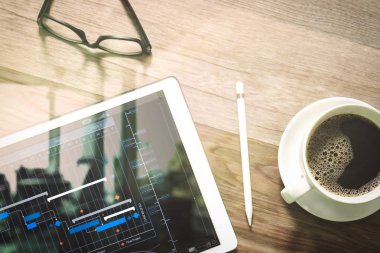 Proje Yöneticisi çalışma ve güncelleştirme görevleri kilometre taşları ilerleme planlama ve Gantt grafiği sanal diyagramı zamanlama. Kahve fincanı ve dijital tablo yerleştirme akıllı klavye, Gözlük, stylus kalem ahşap tablo.