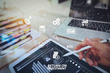 Yatırım getirisi getirisi yatırım göstergesi iş geliştirmek için sanal tablosu içinde. Web sitesi tasarımcısı dijital tablet ve bilgisayar laptop ile akıllı telefon ve dijital tasarım diyagramı ve ahşap masa üzerinde kitap yığını çalışma
