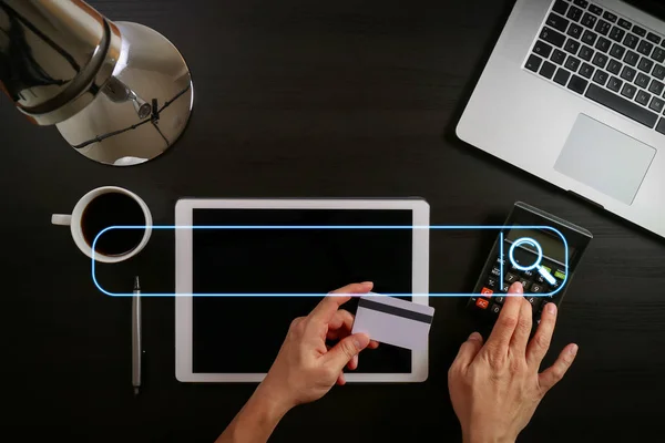 Searching Browsing Internet Data Information Networking Concept with blank search bar.Internet shopping concept.Top view of hands working with laptop and credit card and tablet computer on dark wooden table