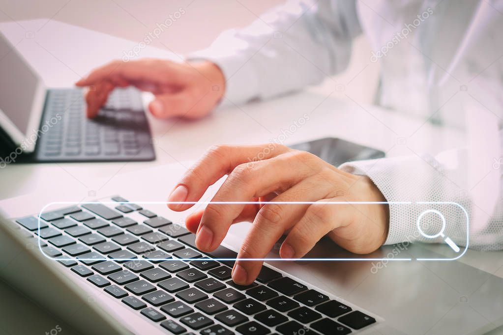 Searching Browsing Internet Data Information Networking Concept with blank search bar.close up of businessman typing digital tablet with keyboard and laptop computer on white desk in modern office