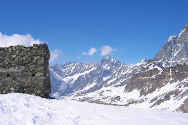 taş duvar, dağın tepesinde, harap bir gözetleme kulesi yakınındaki rüzgârla oluşan kar yığını; güneşli sarp kayalar, dolomit alp dağ yamaçları hackly kabartma