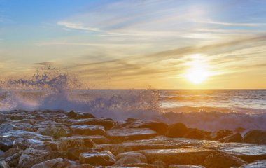İspanya 'nın Cadiz plajında gün batımında deniz dalgaları vuruyor.