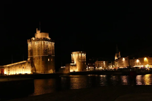 La Rochelle old port (Vieux Port) lit up at night, showing Tour Saint-Nicholas (on the left) and Tour de la Chaine (on the right) guarding the entrance to the harbour