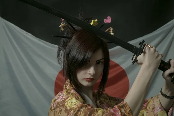 可爱的女孩在和服摆在日本国旗与武士刀 — 图库照片