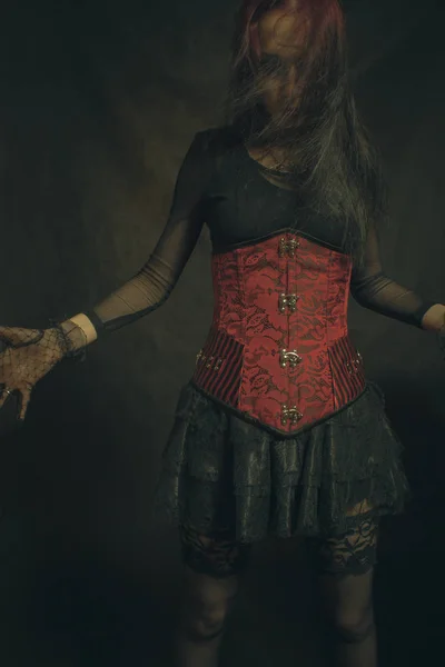 暗い背景上ポーズ赤のコルセットのゴシック様式女の子 — ストック写真
