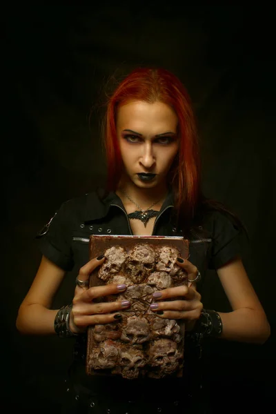 红发哥特式的女孩与老垃圾可怕的书摆在黑暗的背景 — 图库照片