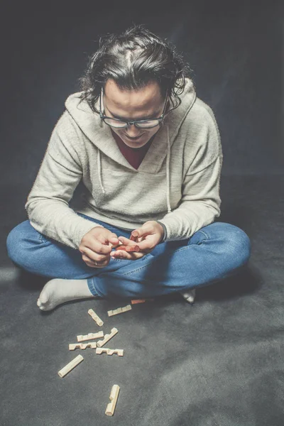 Smart guy with wooden puzzle over dark background.