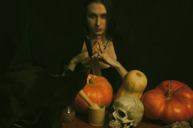 Balkabağı, kafatası ve kara kediyle poz veren gotik kız..