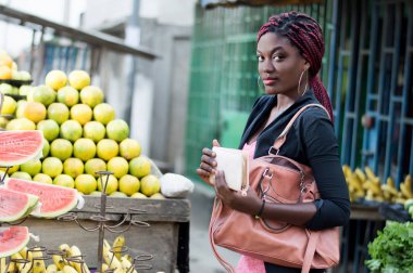 Genç kadının cüzdanını onun elinde bir meyve raf önünde.