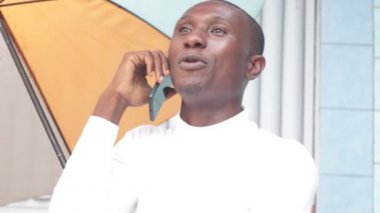 Genç adam telefonda çok renkli bir şemsiye tutan gülümseyerek.