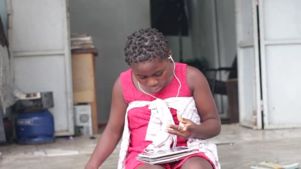象牙海岸阿比让 2018年6月27日 女孩坐在地板上 在一个红色的礼服与听众听音乐的房子入口处前 — 图库视频影像