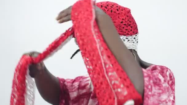 若いアフリカ女性白い背景に分離した赤と白のスカーフと彼女の頭を関係します — ストック動画