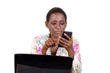 Bir dizüstü bilgisayar önünde oturan genç iş kadını onun cep telefonu beyaz arka plan üzerinde izole danışır