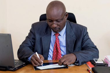 Bir dizüstü bilgisayar ile onun masasında çalışan iş adamı.