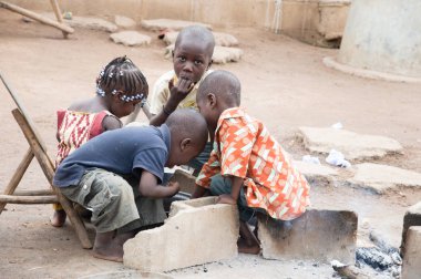 Anekro, Fildişi Sahili - 27 Ağustos 2015: sabah grubunda bir ateş yakın bahçesinde çocuklar yemek. Dört çocuk birlikte paylaşılan bir yemek oturan