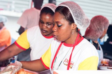 Abican, Fildişi Sahili, 11 Eylül 2016: Abidjan Festivali ızgara zaman bir restoranda aşçı. Kadınlar hizmet yemekleri yükümlü giyinmiş misafirlere onların kefil tarafından sunulan