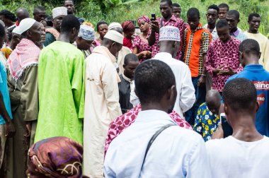 Abican, Fildişi Sahili - 22 Şubat 2017: çok renkli bir eşarp tarafından bağlı ve manyok un, içeren bir tepsi tutarak başını bir taburede oturan Afrikalı kadın kameraya benziyor. Tam attit, tüm Ivorians tarafından sevilen gıda üretimini mevcuttur