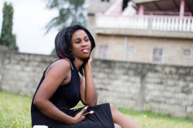 tek başına bir bahçede oturmak ve bir cep telefonu tutan genç kadın