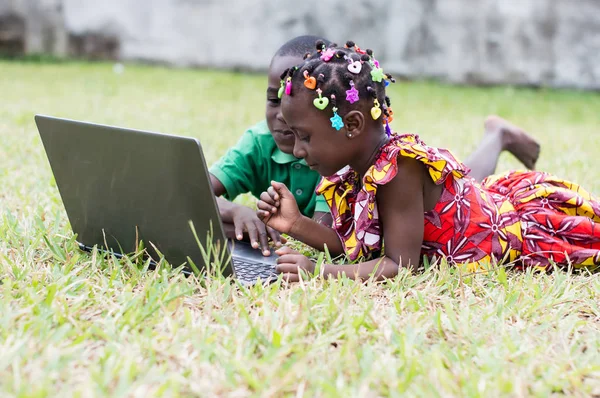 庭に横たわっているラップトップを使用して幸せな子供 — ストック写真