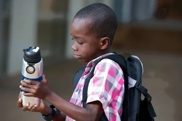 彼は彼の手で保持している水の彼の瓶を見て男子生徒 — ストック写真