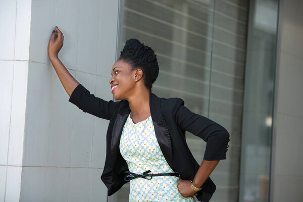 smiling businesswoman or student standing hands on hip and wall.