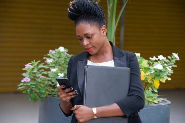 cep telefonu seyir ve bir dizüstü bilgisayar tutan genç iş kadını.