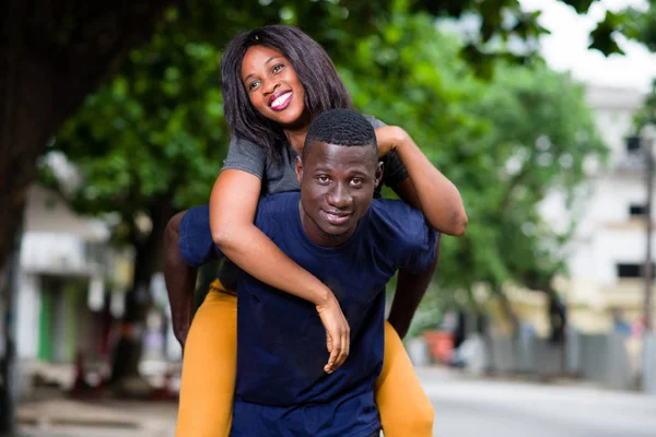 Young smiling man standing and holding his girlfriend on the bac — Stock Photo, Image